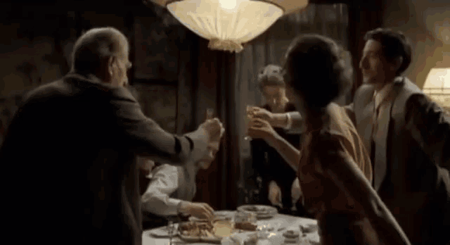 a group of people are sitting around a table toasting with wine glasses .