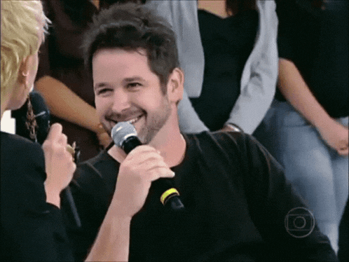 a man is smiling while holding a microphone in his hand