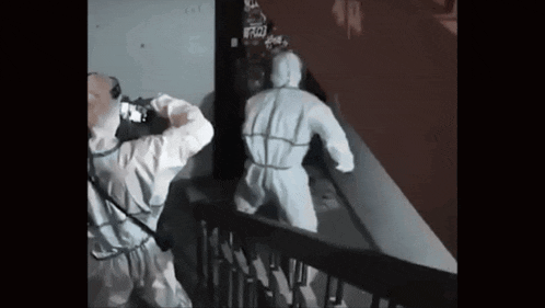 a man in a protective suit is walking down a set of stairs .