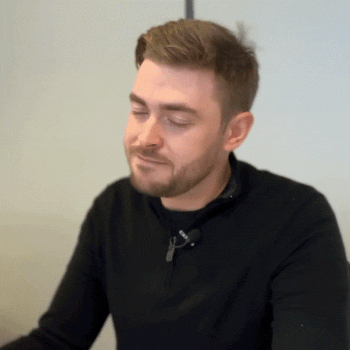 a man with a beard is wearing a black sweater with a zipper on the front