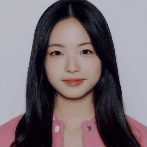 a woman with long black hair and red lips is wearing a pink jacket