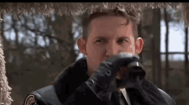 a man in a police uniform is drinking from a cup while wearing gloves .