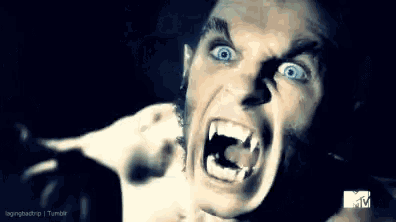 a close up of a man 's face with fangs and a mtv logo in the corner