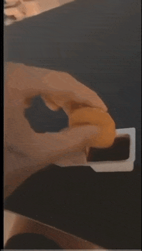 a person is holding a piece of food in their hand with a napkin in the background .