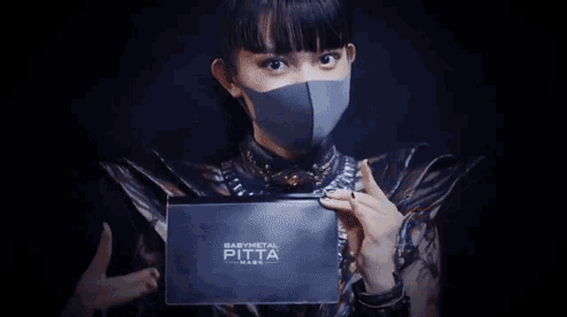 a girl wearing a mask holds a baby metal purse