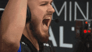 a man wearing a headset is screaming in front of a sign that says min