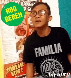 a boy wearing glasses and a black familia shirt