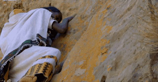 a person in a white blanket is crawling up a hill