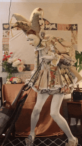 a woman in a clown costume holds a vacuum cleaner in front of a sign that says clown baby