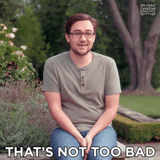 a man with glasses sits on a bench with the words that 's not too bad behind him