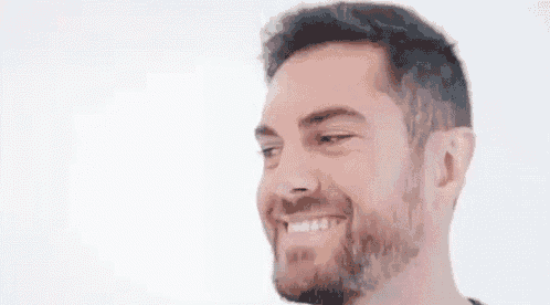 a close up of a man with a beard smiling against a white background .