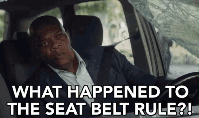 a man in a suit is sitting in a car with the words " what happened to the seat belt rule "