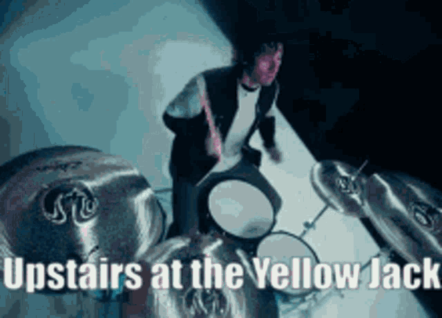a man is playing drums with the words upstairs at the yellow jack