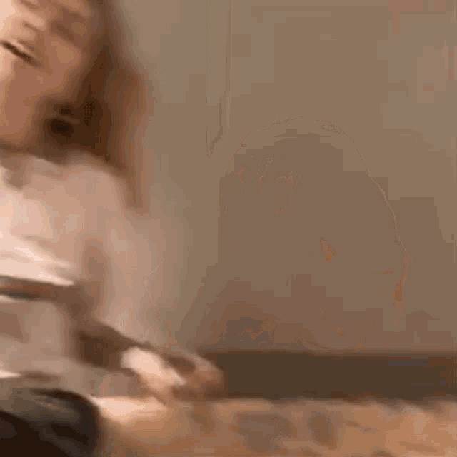 a blurry picture of a man sitting on a bed holding a piece of paper .