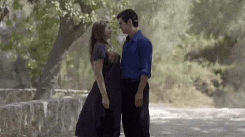 a man and a woman are standing next to each other and looking into each other 's eyes