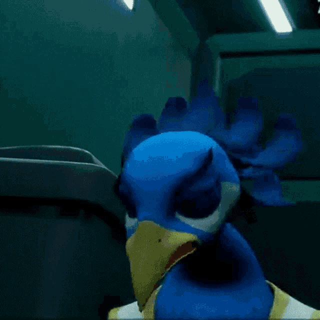 a blue bird with a yellow beak is standing in front of a trash can .