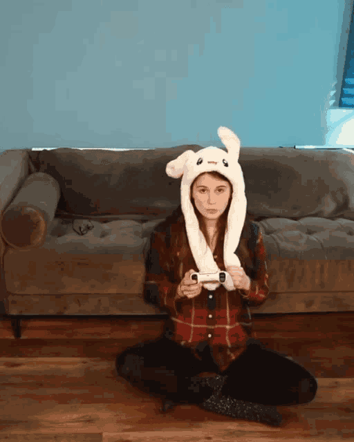 a woman wearing a bunny hat is sitting on the floor holding a game controller