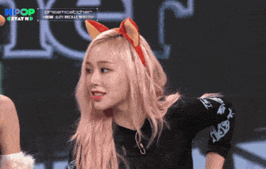 a girl with pink hair is wearing a headband with cat ears