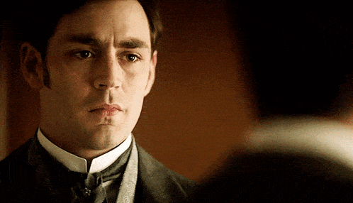 a man in a suit and tie is looking at another man 's face