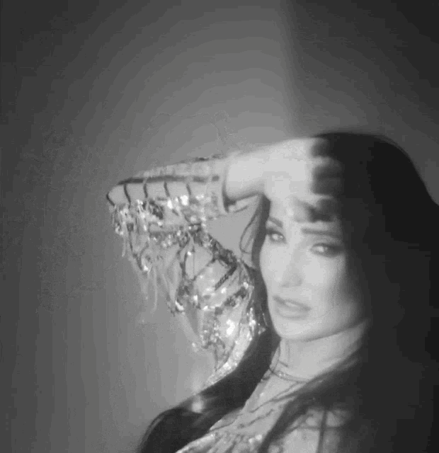 a black and white photo of a woman covering her face with her hand .