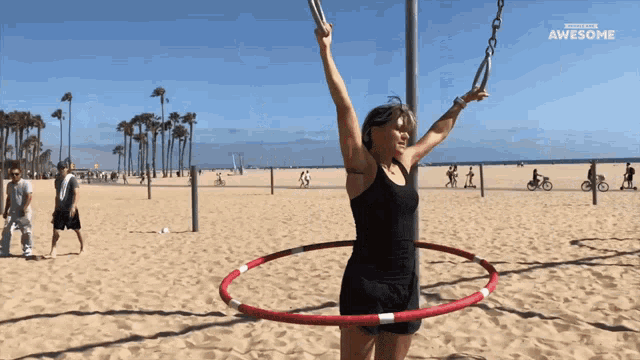 a woman is doing a hula hoop exercise on a beach with a headline that says awesome