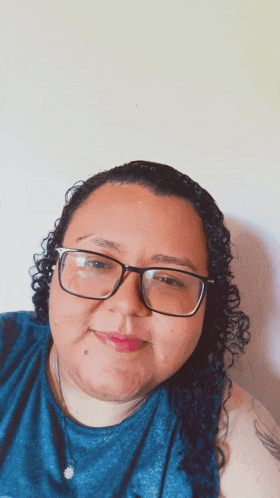 a woman wearing glasses and a blue shirt is smiling for the camera