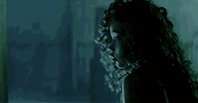 a woman with long curly hair in a dark room