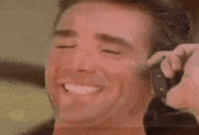 a close up of a man 's face with a person holding a gun to his ear .