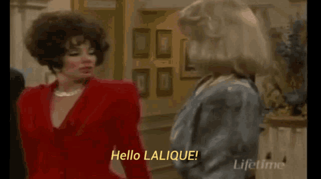 a woman in a red jacket says hello lalique to another woman in a blue jacket