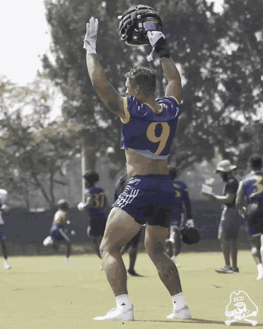 a football player wearing a number 9 jersey holds up a helmet
