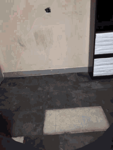 a corner of a room with a window and a shadow on the wall