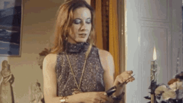 a woman in a dress is holding a candle in her hand
