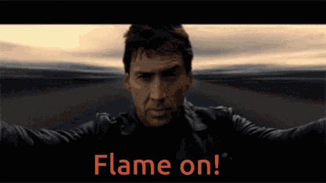 a man in a leather jacket stands in front of a flame on sign