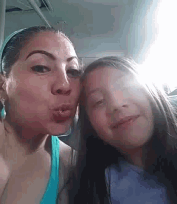 a woman and a girl are kissing each other on the cheek while taking a selfie .
