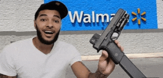 a man is holding a gun in front of a wal mart sign .