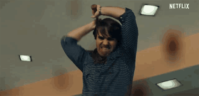 a man is standing in a room with his hands on his head and a netflix logo behind him .