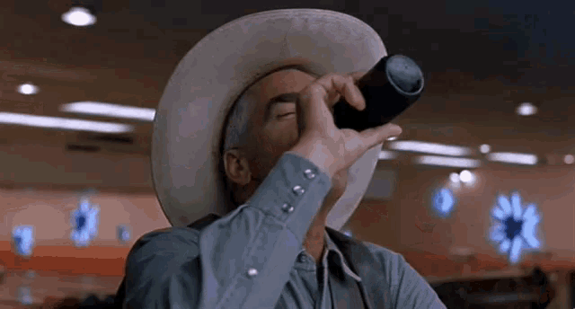 a man in a cowboy hat drinking from a bottle