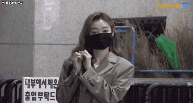 a woman wearing a mask is standing in front of a sign that says newsen .
