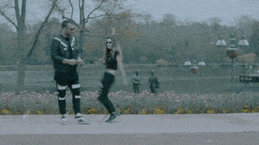 a man and a woman are standing on a sidewalk near a lake