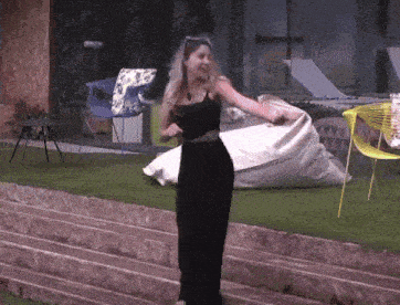 a woman in a black dress is dancing in front of a chair