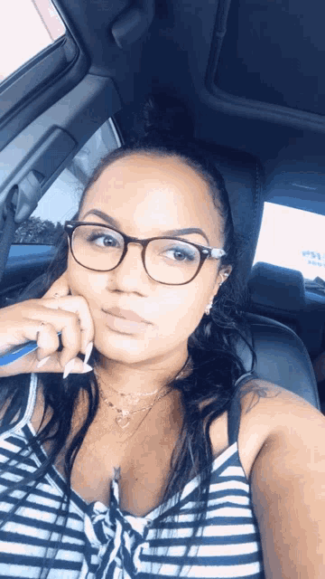 a woman wearing glasses is taking a selfie in the back seat of a car