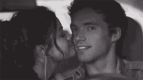 a man and a woman are sitting next to each other in a car and hugging .