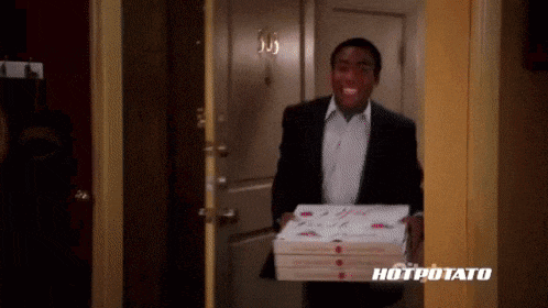 a man in a suit is carrying a stack of pizza boxes
