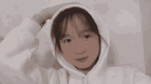 a girl wearing a white hoodie and a watch on her wrist