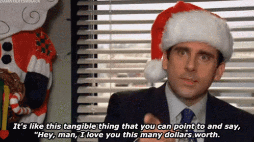 a man in a suit and tie is wearing a santa hat and talking to another man .