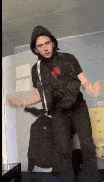 a young man wearing a hooded jacket and a black shirt with a red stripe on the sleeve is dancing
