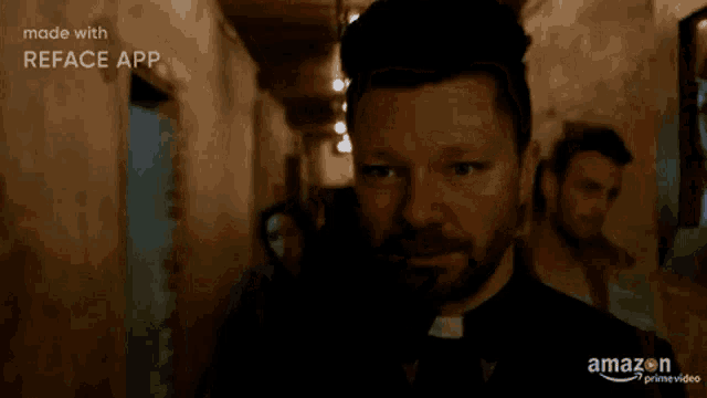 a man with a beard is standing in a dark hallway looking at the camera .