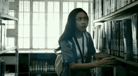 a woman is searching for books in a library .