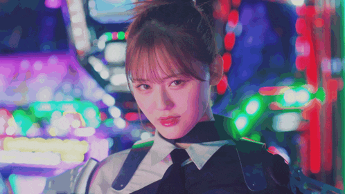 a woman in a ponytail looks at the camera in front of a colorful background