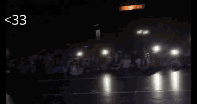 a crowd of people are gathered in a dark room and the number 33 is visible